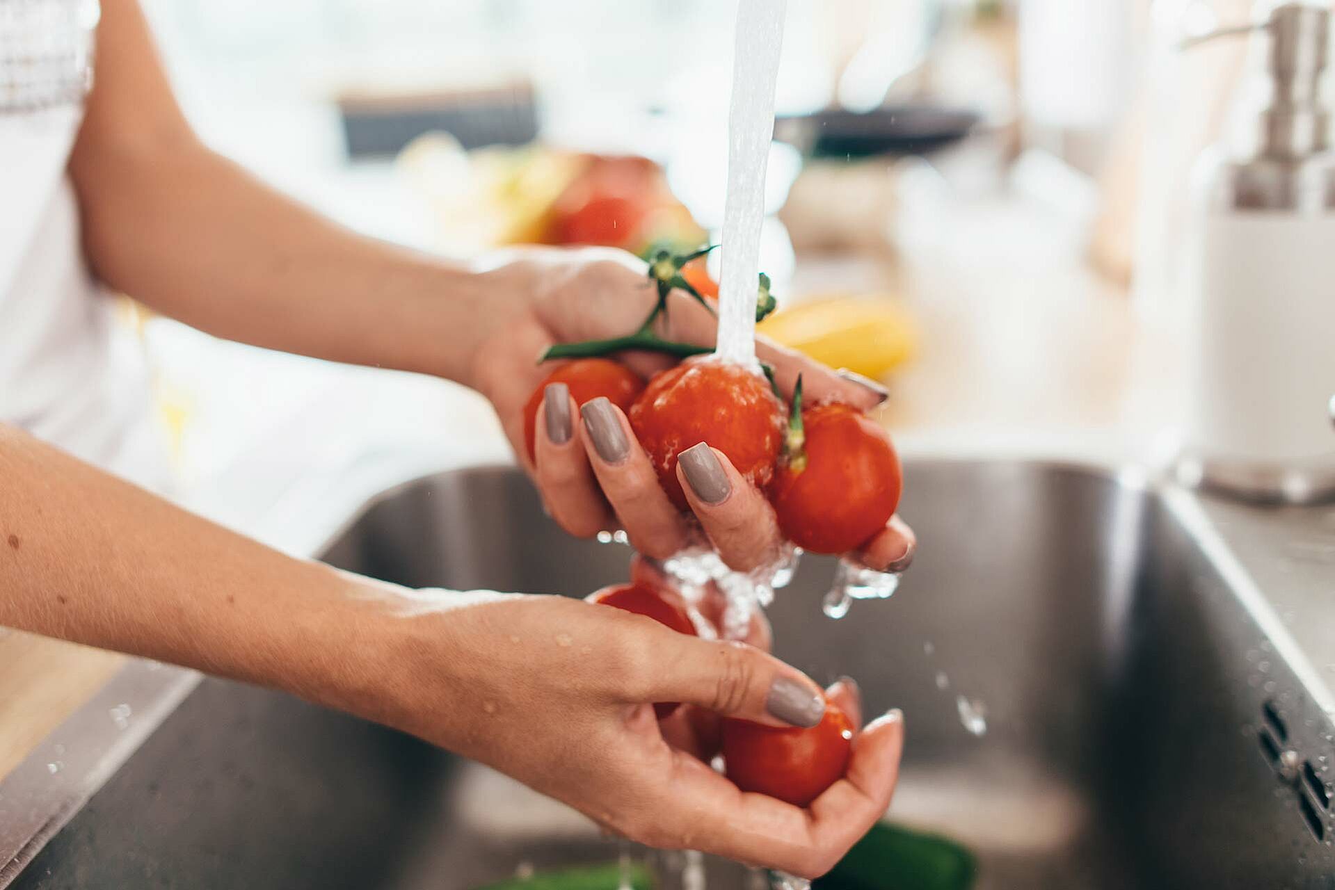 Frau wäscht Tomaten in der Küche