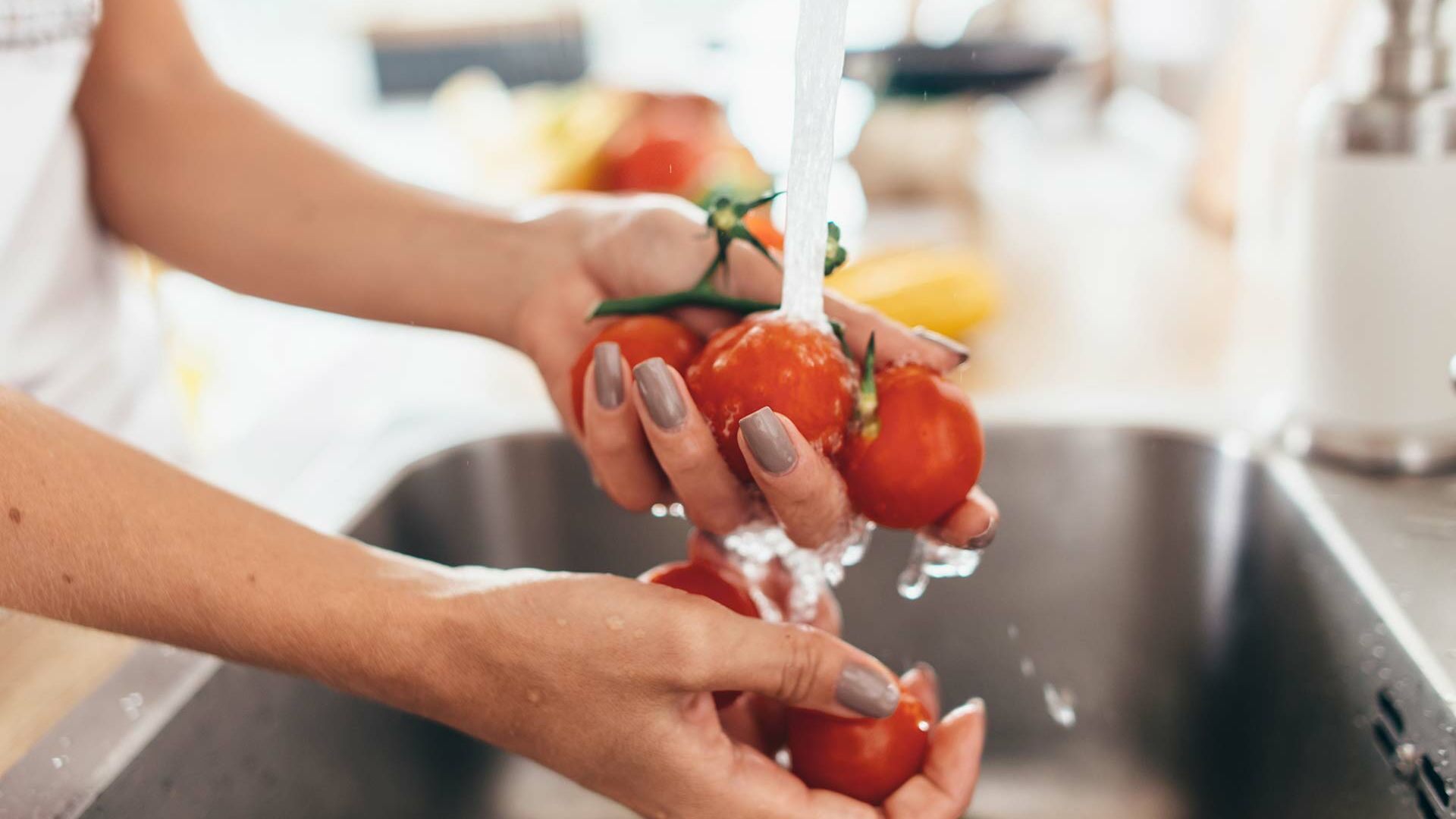 Frau wäscht Tomaten in der Küche