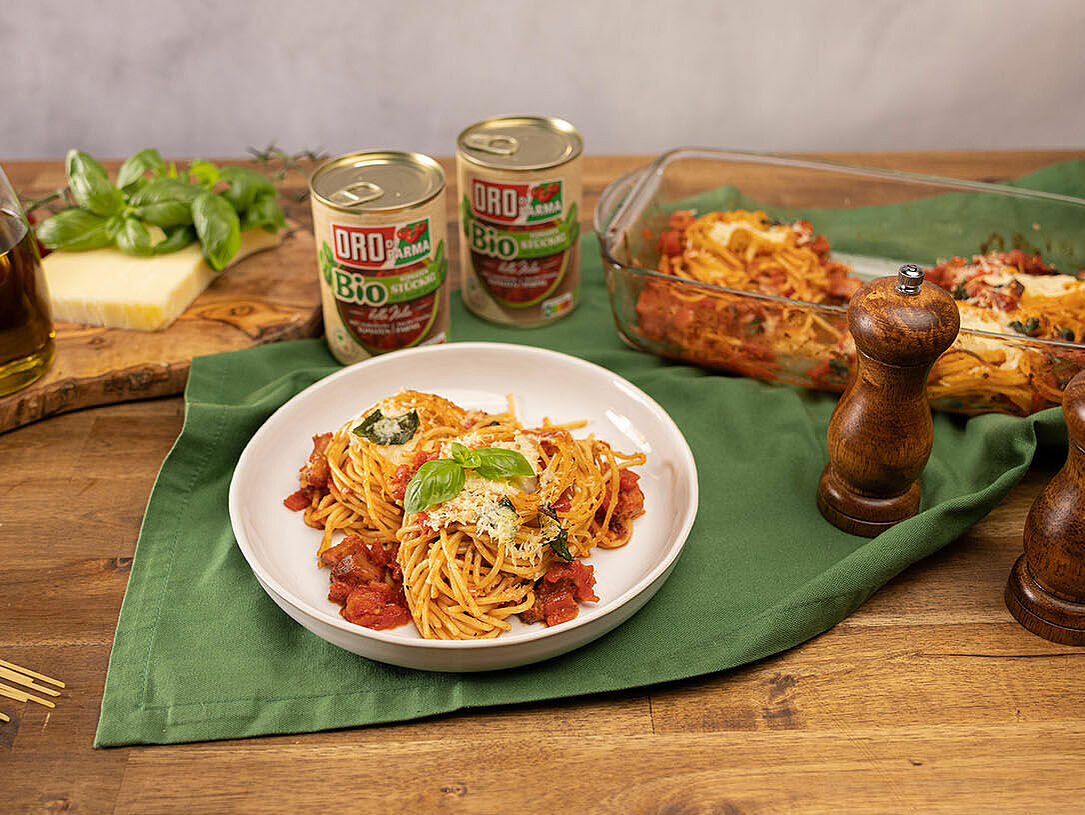 Ein Tisch mit Nudeln, Kräutern und Spaghetti con Provolone e Guanciale in einer Auflaufform aus dem Ofen