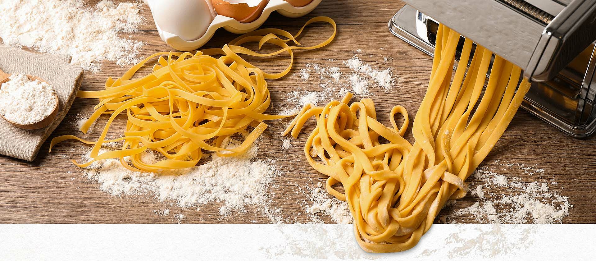 Pasta secca in Nudelmaschine auf Holztisch