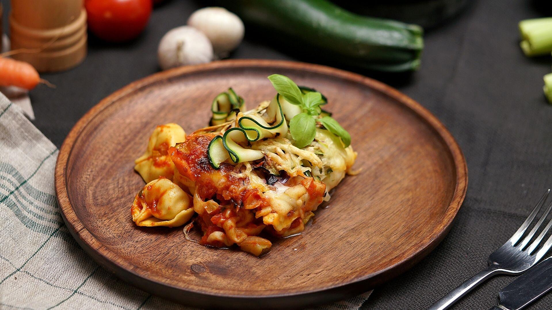 Ein Holzteller mit einer Portion Tortellini al forno
