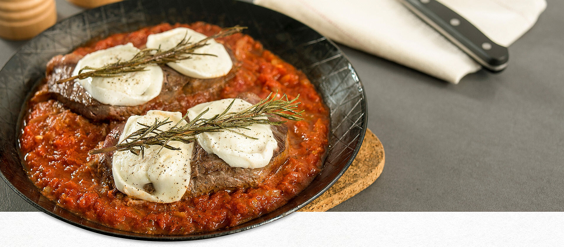 Eiserne Pfanne mit Bistecca con Pomodoro steht auf einem Tisch