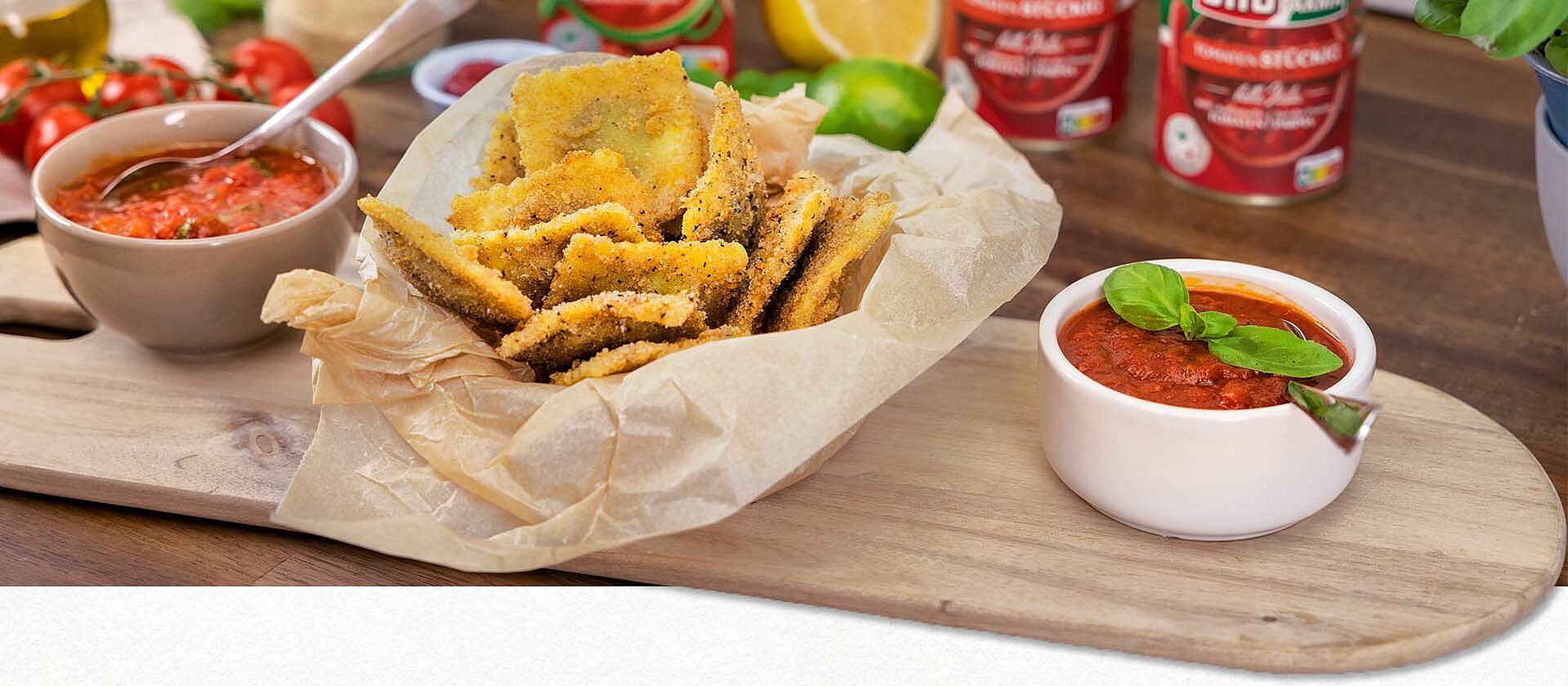 Frittierte Ravioli auf einem Brettchen mit Tomaten-Dips