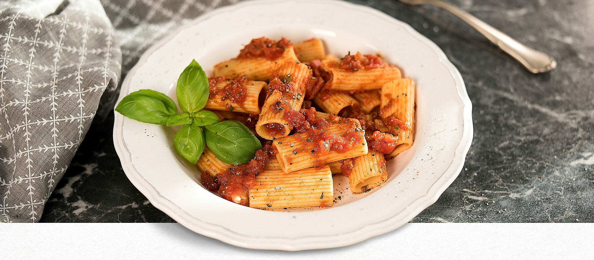 Ein weißer Pastateller mit Rigatoni in Balsamico-Tomatensauce 