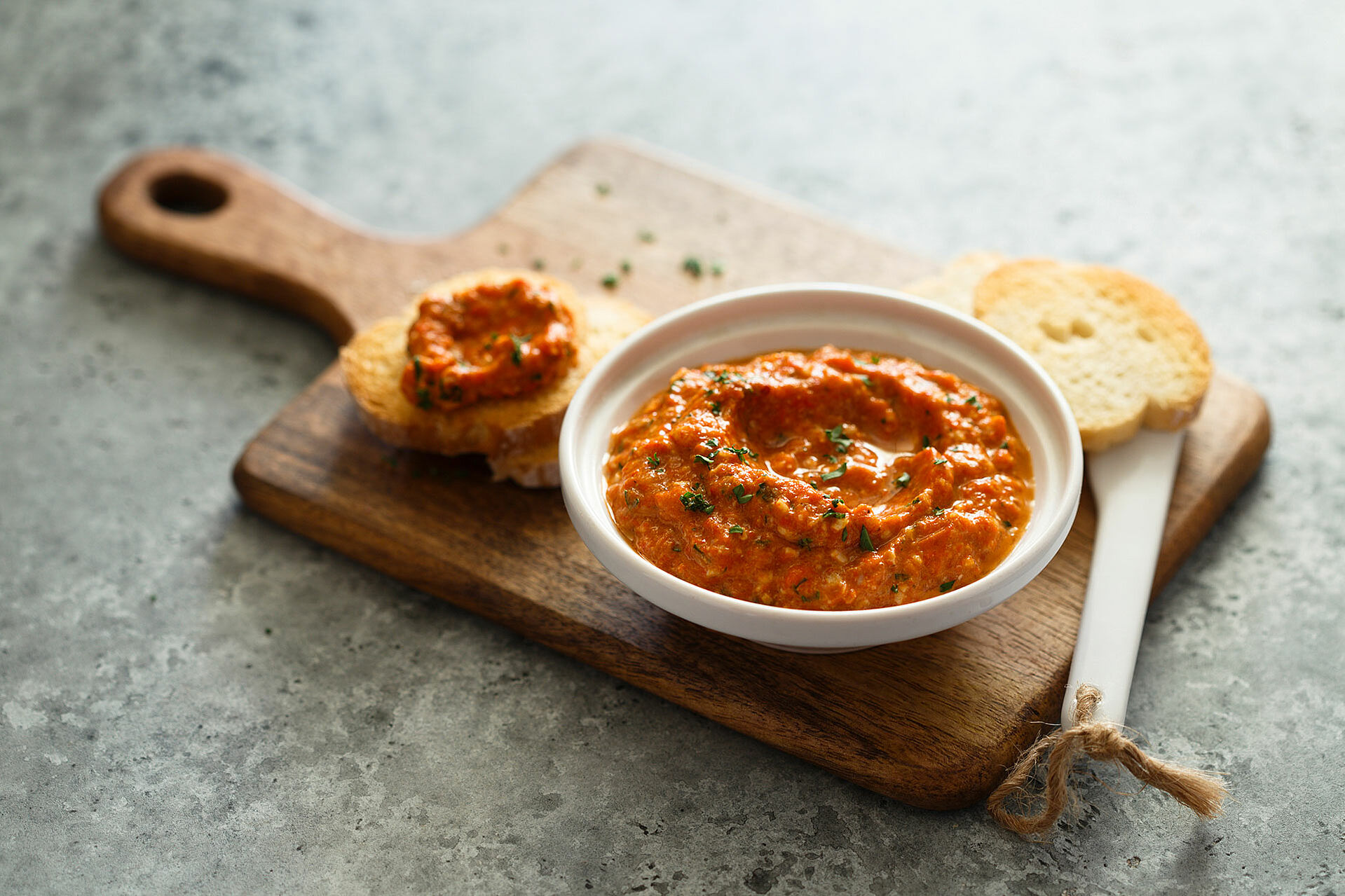 Dip aus Tomate in einem Schälchen auf einem Holzbrett