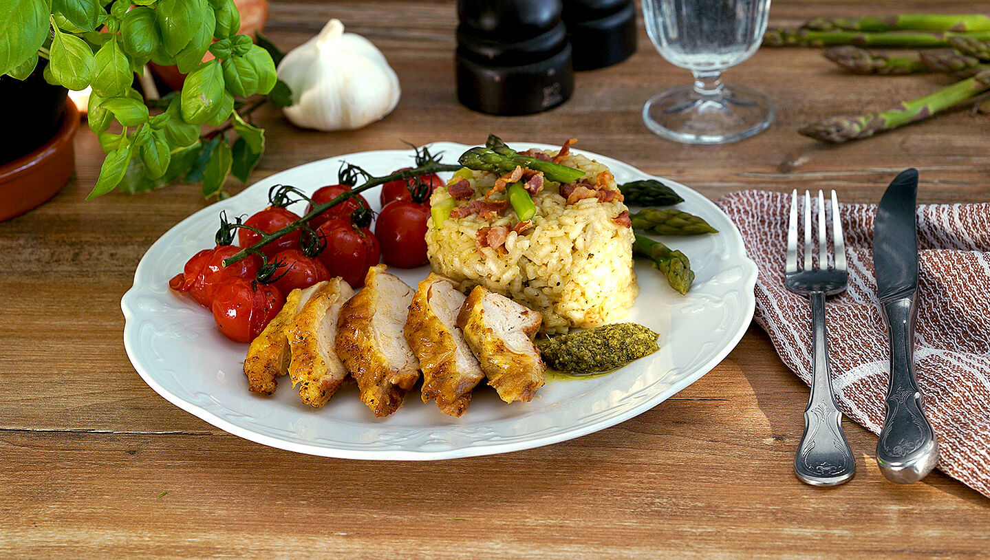 Ein Teller mit einem Tomatenzweig, Risotto und in Scheiben geschnittenem Huhn