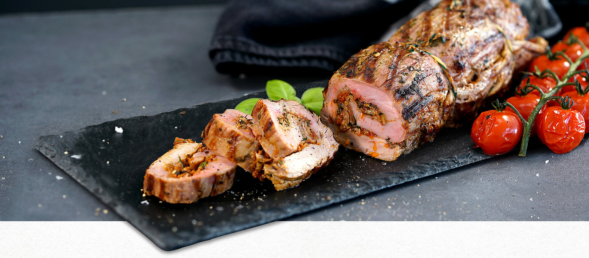 Eine Schiefer-Servierplatte mit gefülltem Schweinefilet in Scheiben geschnitten