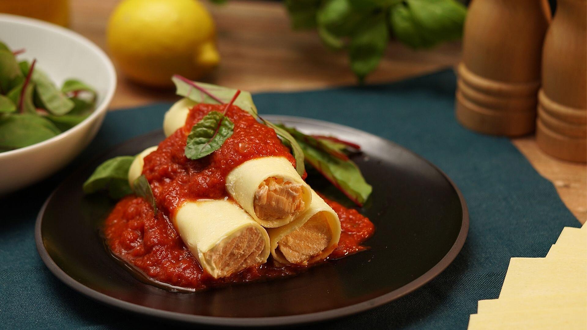 Lachs-Cannelloni mit Tomatensauce auf einem Teller angerichtet