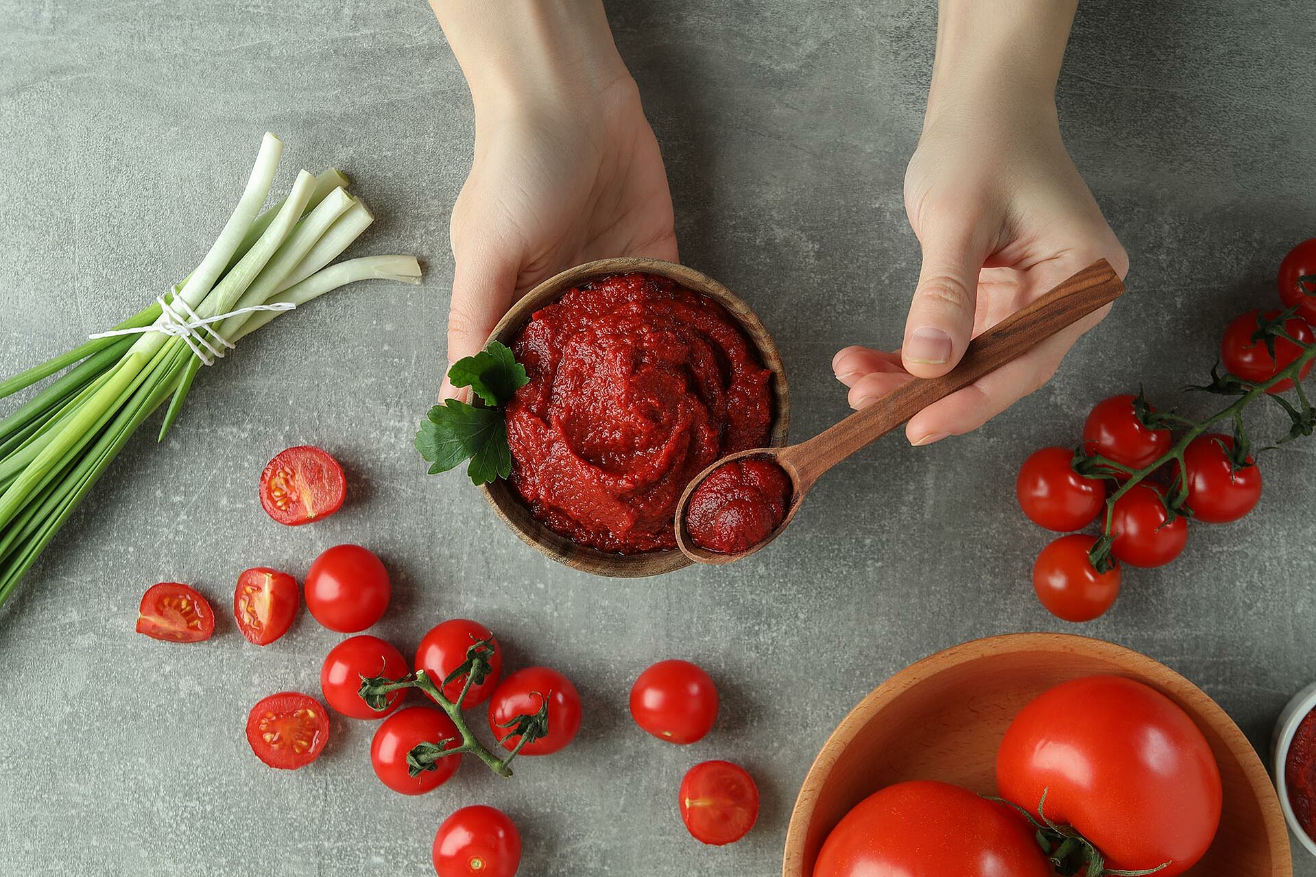 Tomatenmark in einer Holzschüssel und auf einem Holzlöffel