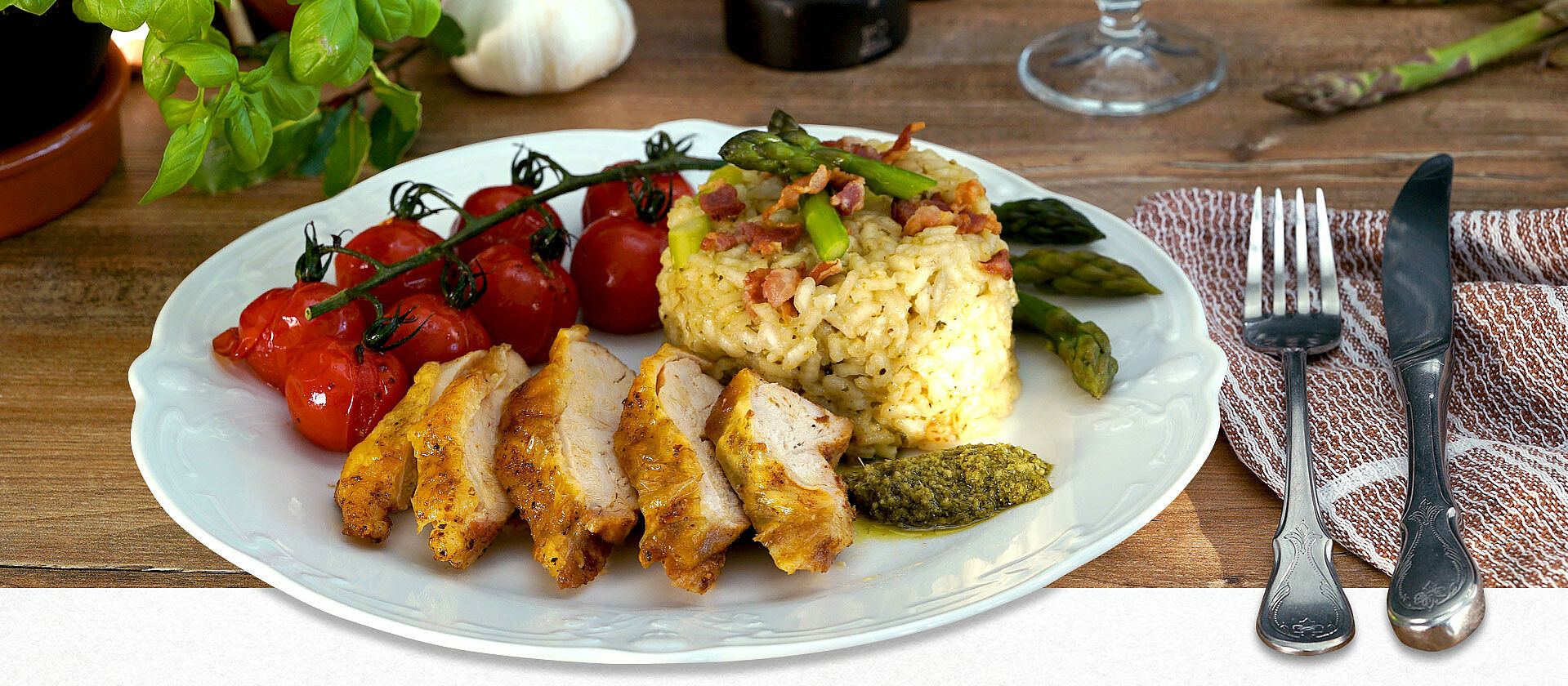 Ein Teller mit einem Tomatenzweig, Risotto und in Scheiben geschnittenem Huhn