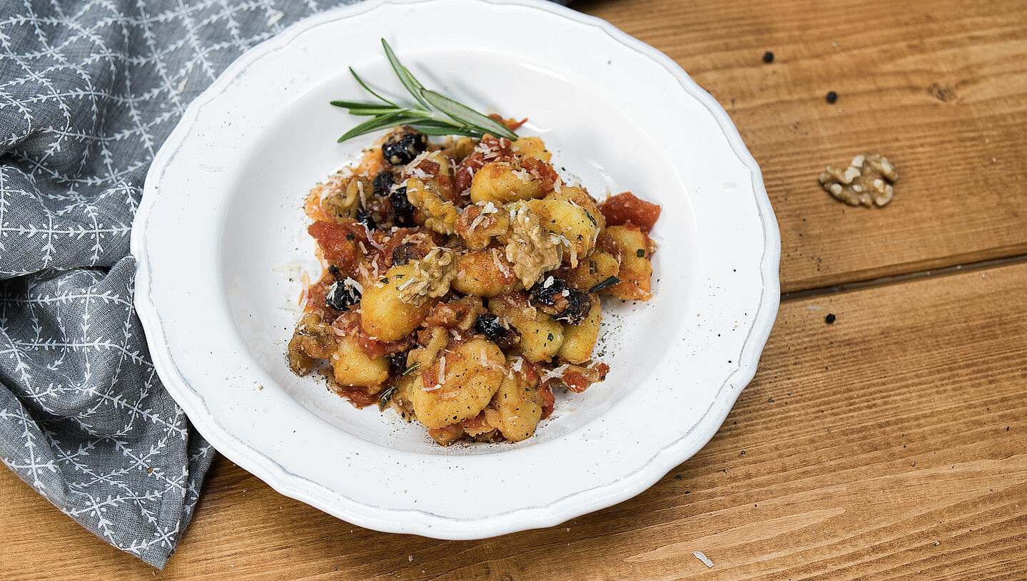 Rosmarin-Gnocchi mit Tomaten-Cranberry-Sauce auf einem Pastateller angerichtet