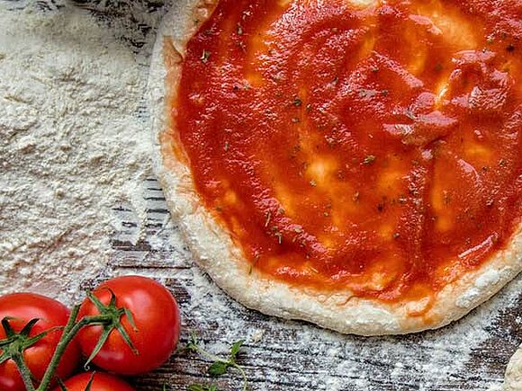 Pizzateig mit Tomatensauce und Zutaten