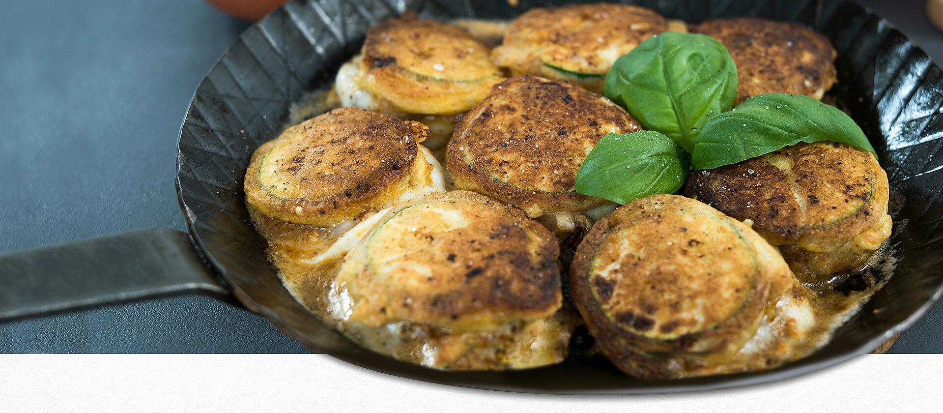 Überbackene Zucchini-Mozzarella-Scheiben in einer gusseisernen Pfanne