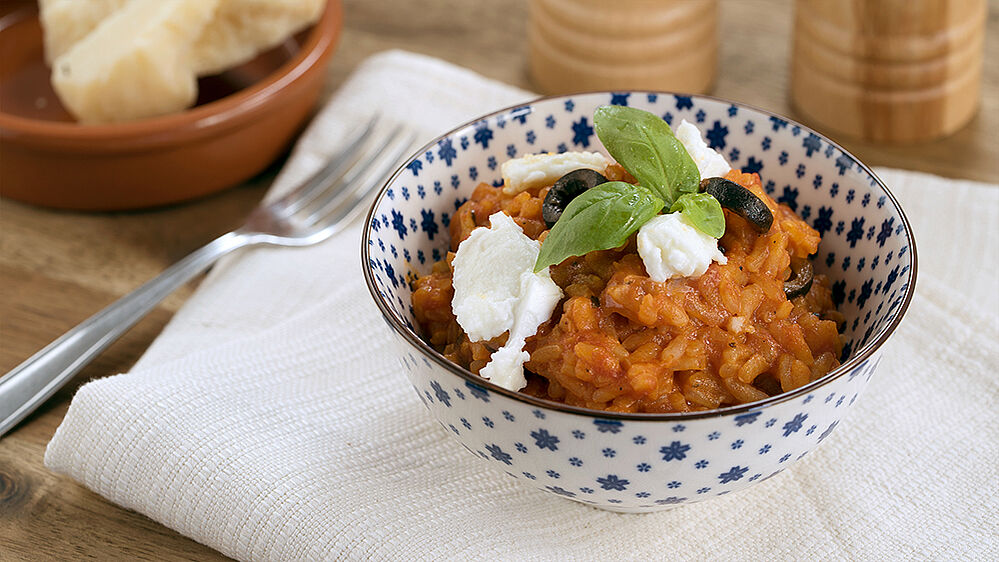 Alternativ-Text:	Eine Schale gefüllt mit Tomaten-Risotto, garniert mit Oliven, Mozzarella und Basilikum