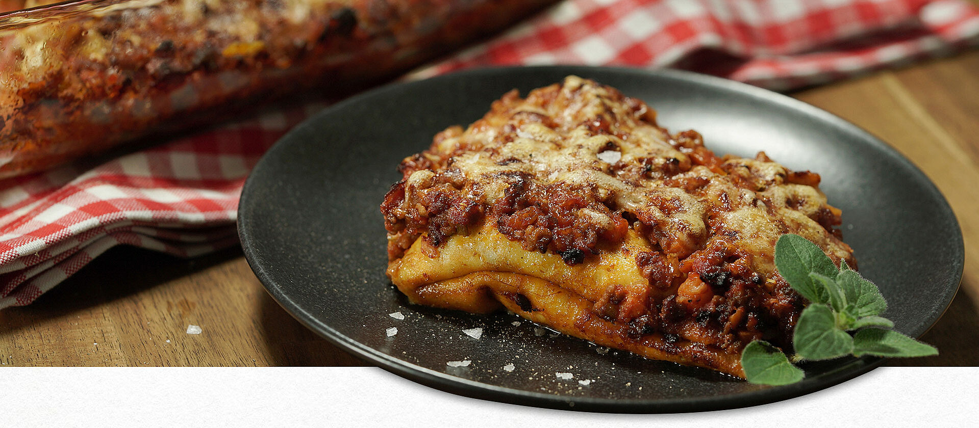 Crespelle - italienische Pfannkuchen gefüllt mit Bolognese auf einem schwarzen Teller