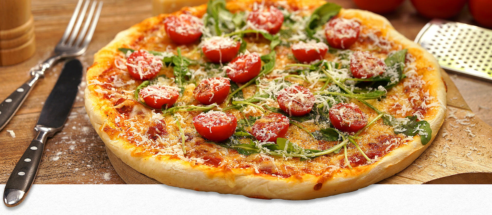 Selbstgemachte Pizza mit Rucola, Tomaten und geriebenem Käse