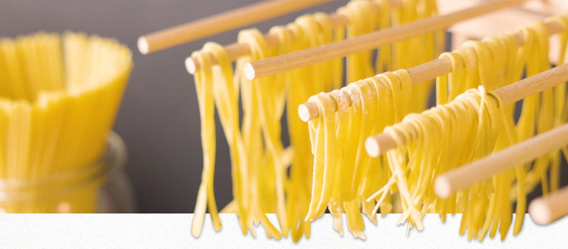 Selbstgemachte Pasta hängt zum Trocknen an mehreren Holzstäben