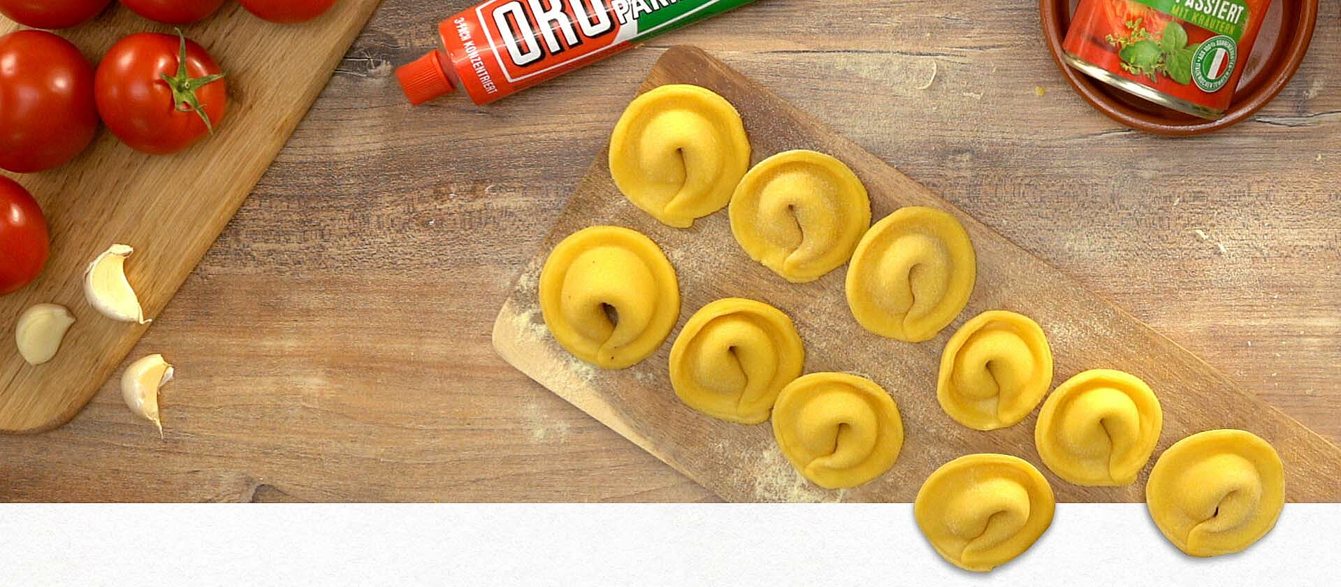 Frische Tortellini liegen auf einem Holzbrett