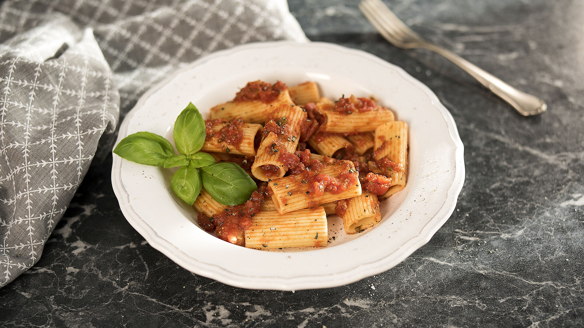 Ein weißer Pastateller mit Rigatoni in Balsamico-Tomatensauce 