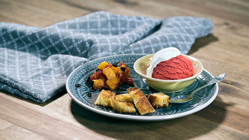 Auf einem Teller liegen gebratene Brioche-Stücke, daneben eine Schüssel mit Tomatensorbet und Tomaten-Mango-Kompott