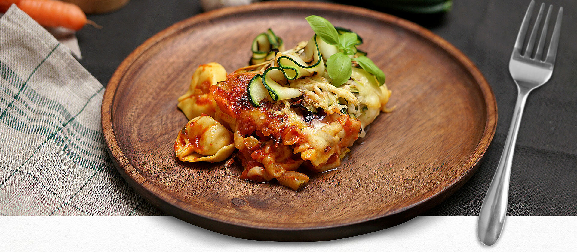 Ein Holzteller mit einer Portion Tortellini al forno