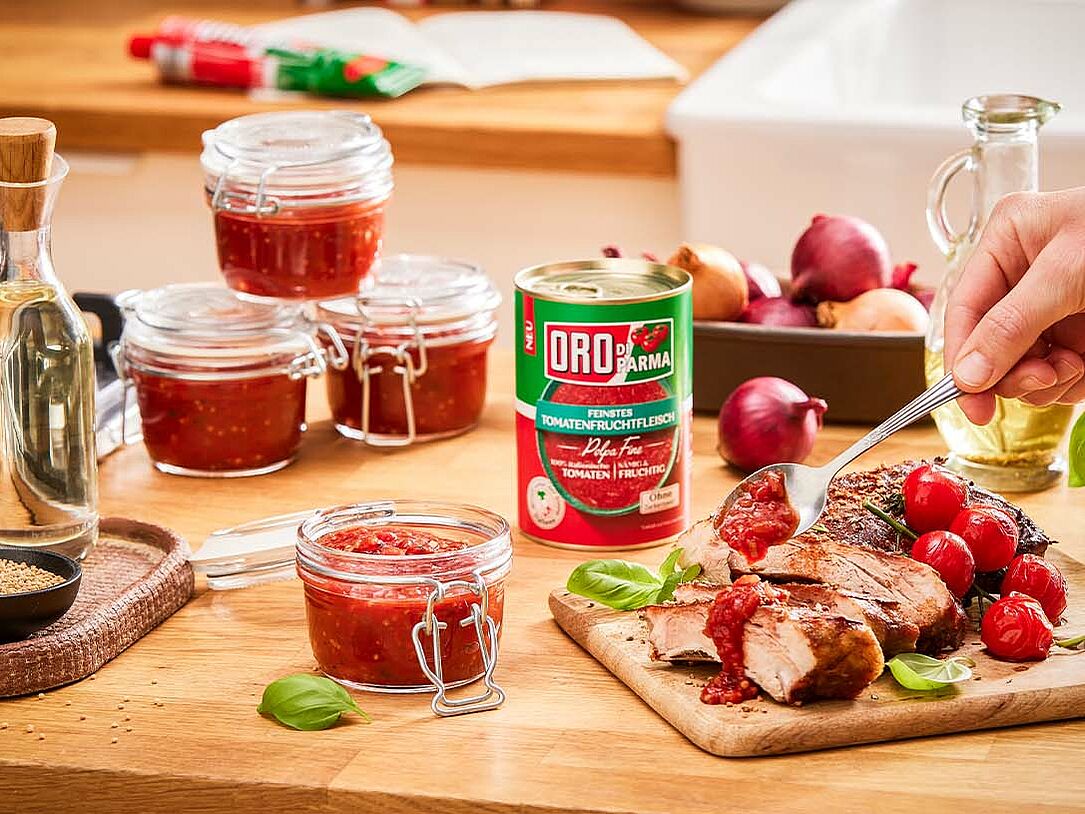 Hand gibt selbstgemachtes Tomaten Chutney über Fleisch