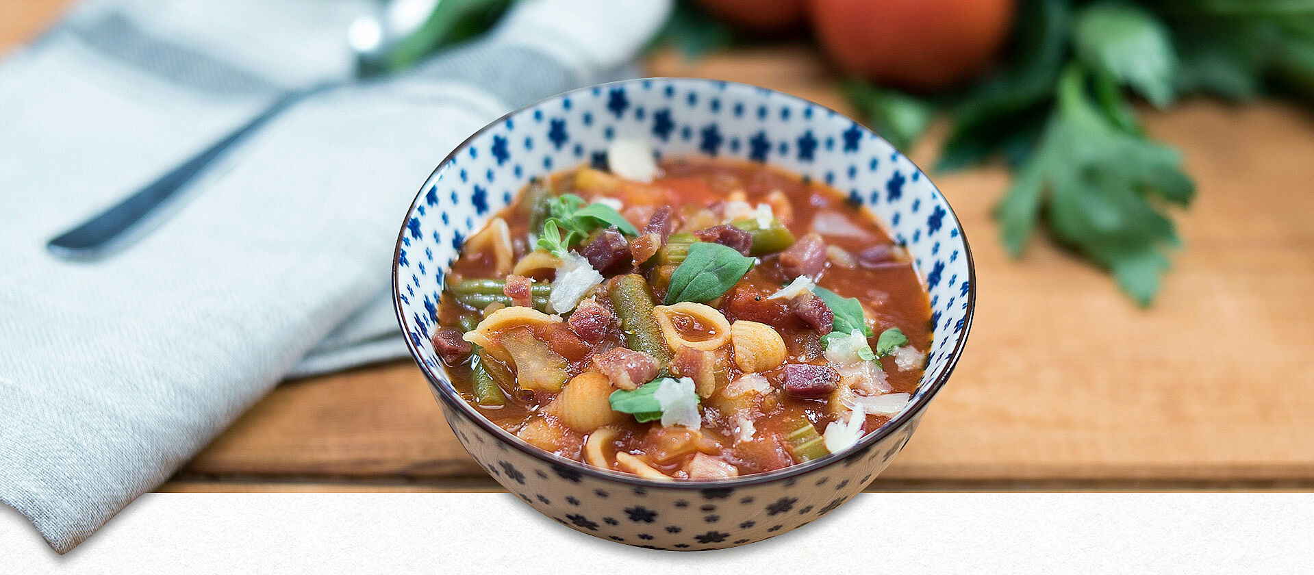 Minestrone in einer blau-weißen Schüssel mit Kräutern dekoriert