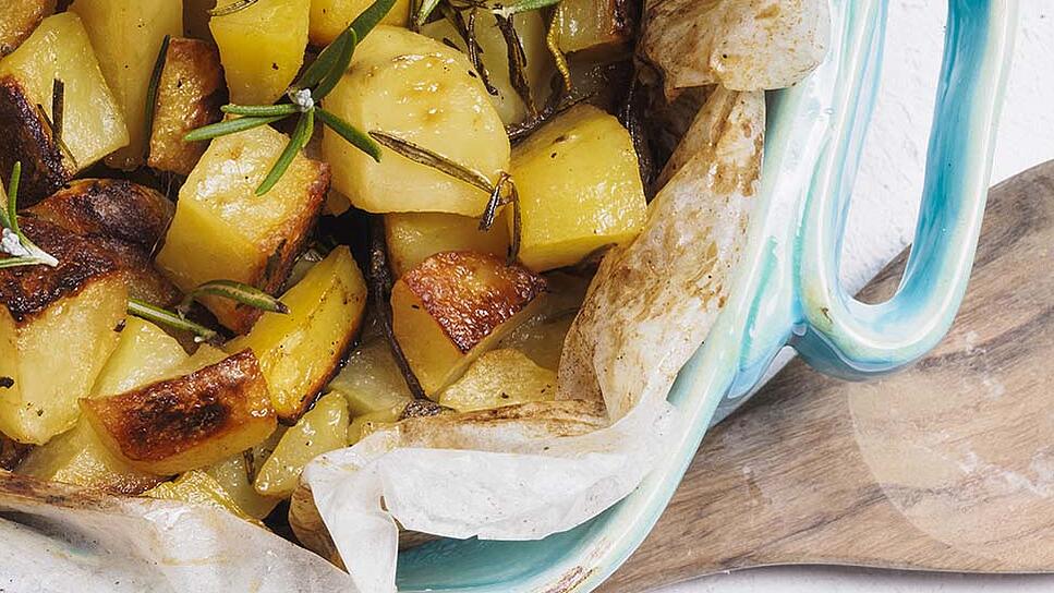 A baking dish filled with baked potatoes, garnished with rosemary