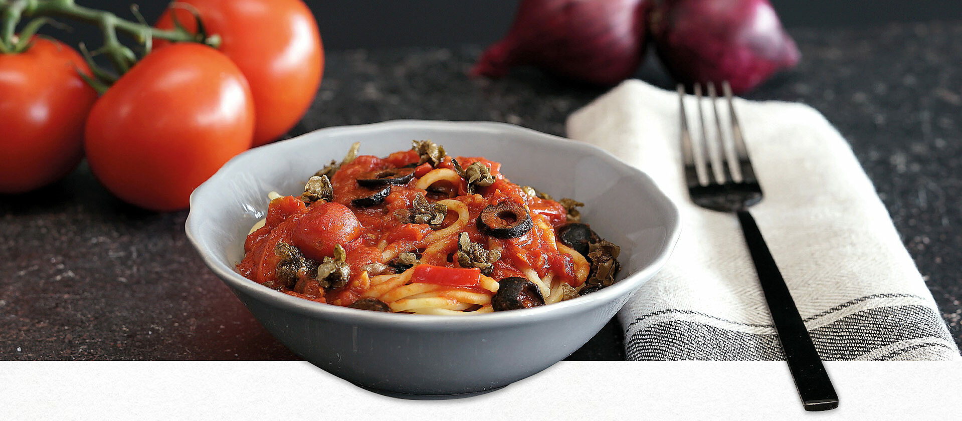 Eine Schüssel mit Spaghetti in Tomatensauce und Oliven