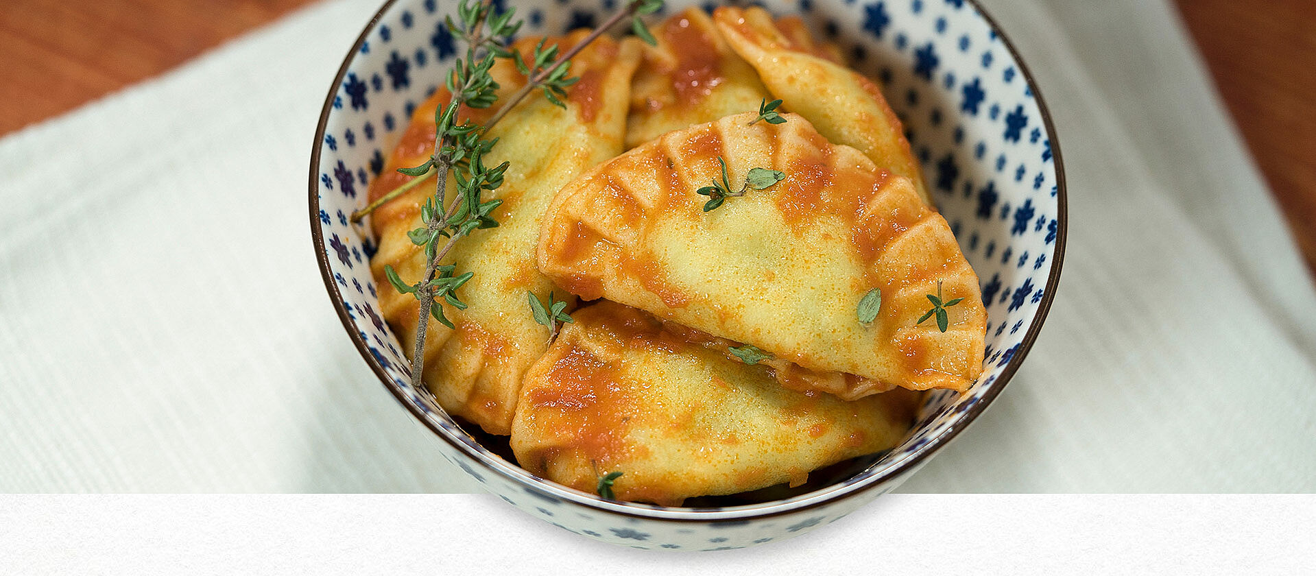 Ravioli mit Tomatensauce in einer Schüssel angerichtet und mit Kräutern garniert