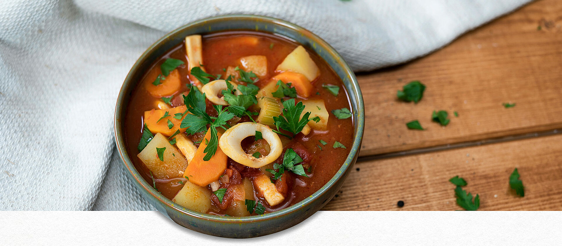 Eine Schüssel gefüllt mit Tintenfischsuppe, garniert mit Petersilie