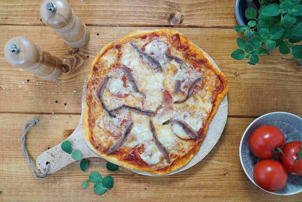 Pizza mit Sardellen auf einem Holzbrett 
