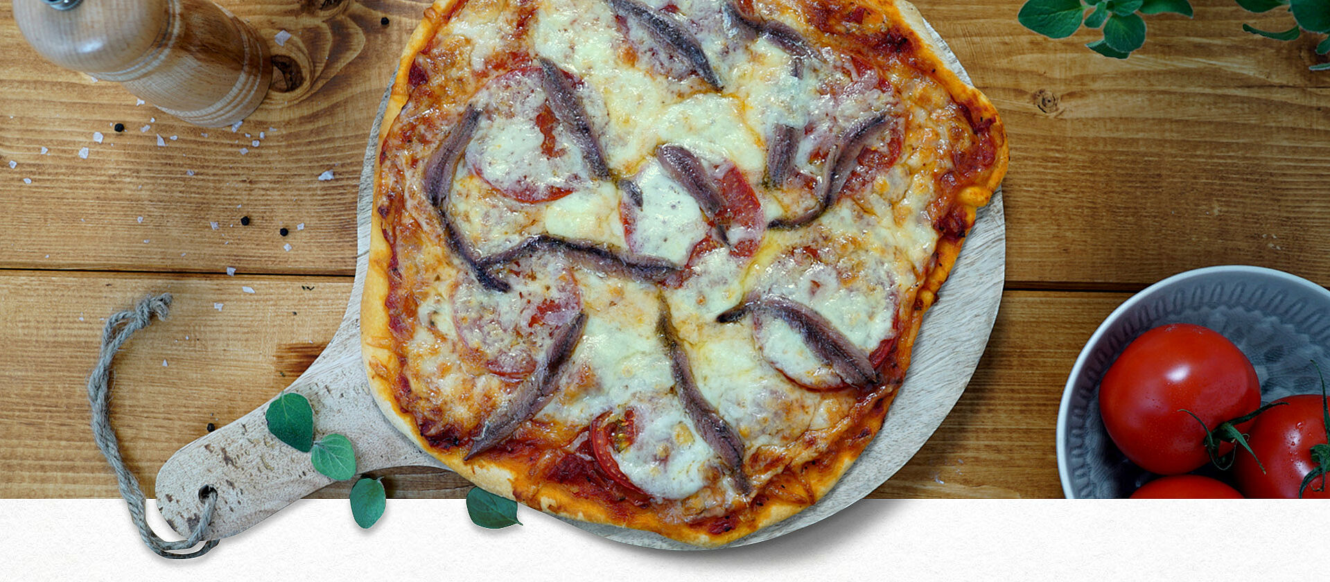 Pizza mit Sardellen auf einem Holzbrett 