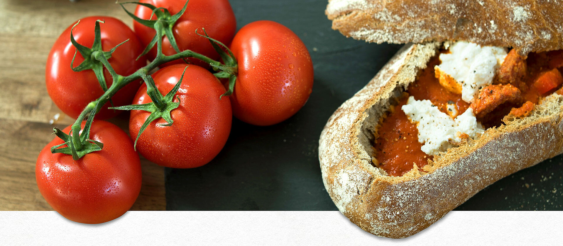 Paprika-Tomatensuppe in einem Ciabatta-Brot serviert, daneben ein Tomatenzweig
