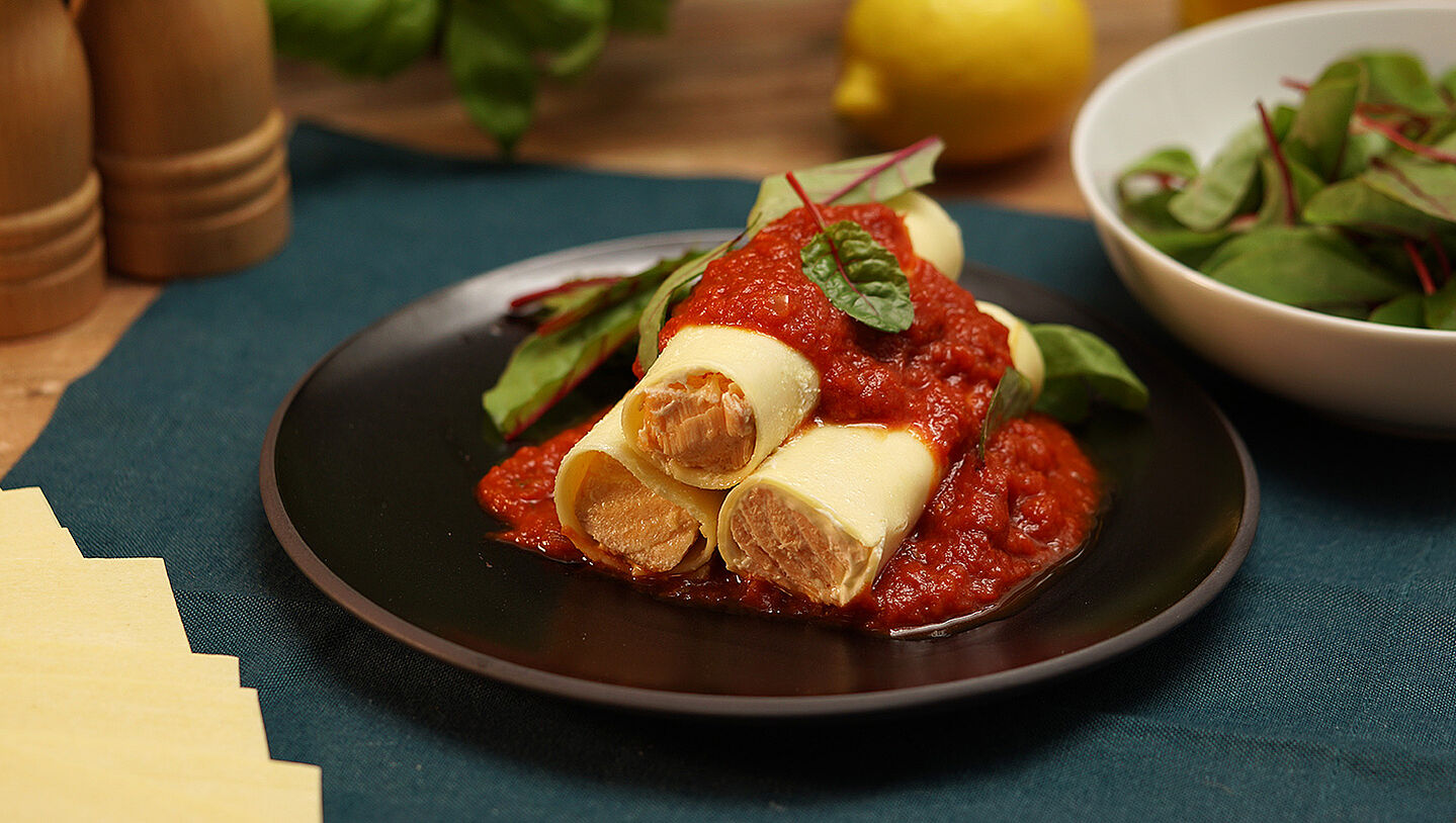 Lachs-Cannelloni mit Tomatensauce auf einem Teller angerichtet