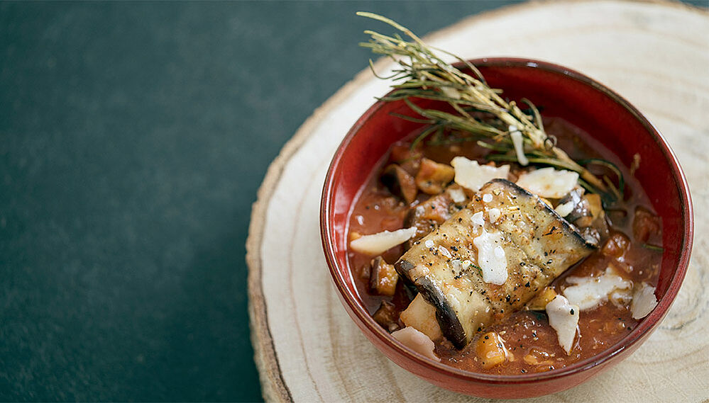 Ein geschmortes Auberginenröllchen in Tomatensauce in einer Schüssel