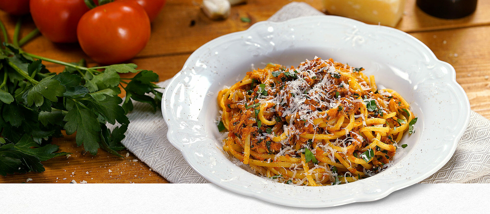 Linguine mit Thunfisch auf einem Pastateller mit geriebenem Parmesan garniert