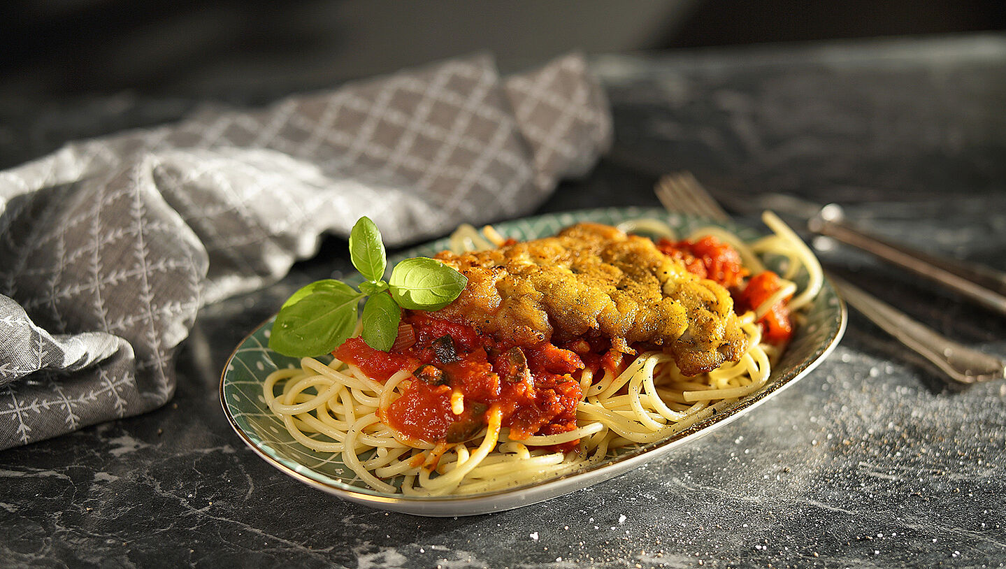 Ein Teller mit Pasta, Sauce und Schnitzel Mailänder Art