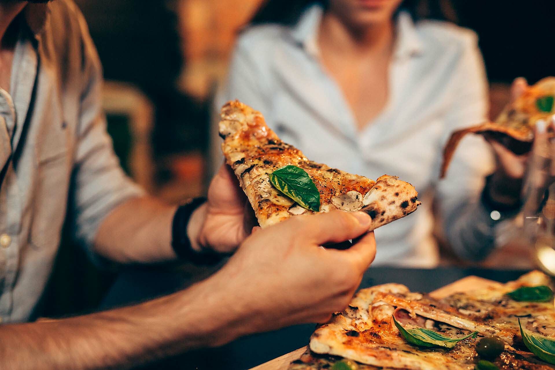 Pizzastück wird in der Hand gehalten