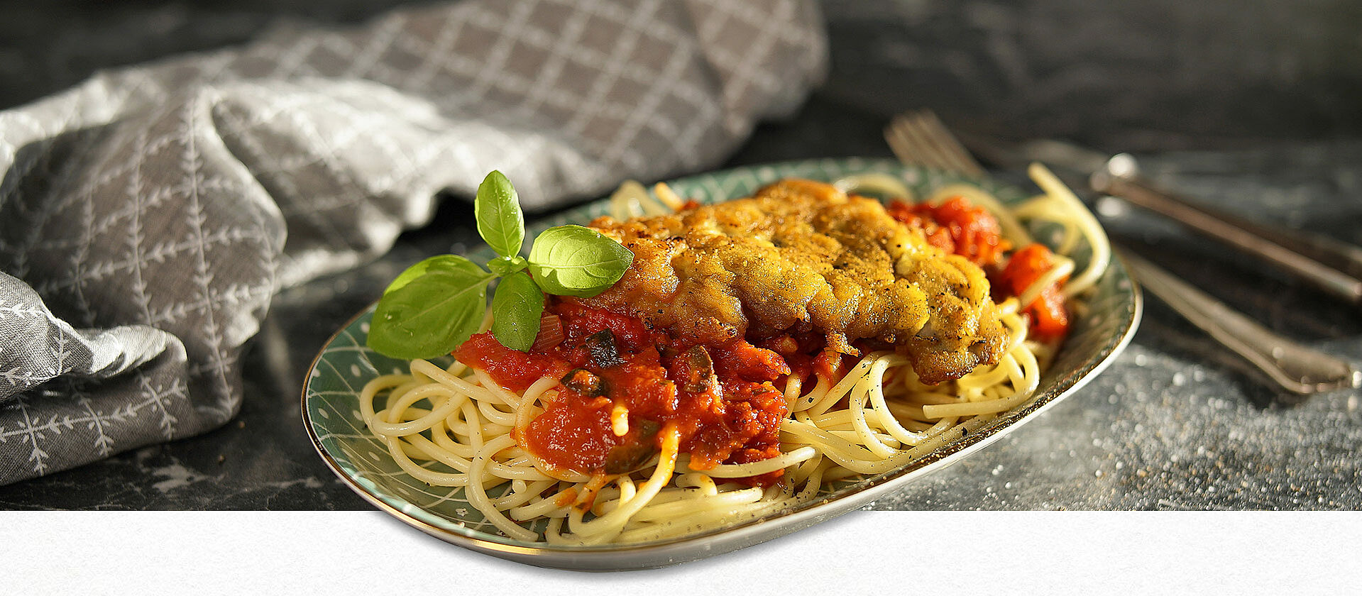 Ein Teller mit Pasta, Sauce und Schnitzel Mailänder Art