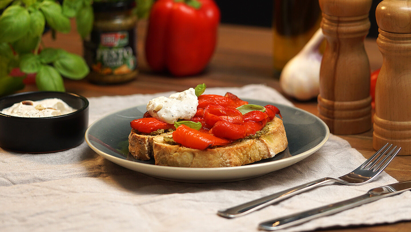 Zwei Scheiben Ciabatta-Brot mit gegrillter Paprika und Ricotta-Pinienkercreme belegt