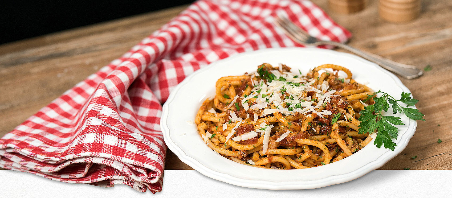 Bucatini-Nudeln mit Tomatensauce auf einem weißen Teller angerichtet. 