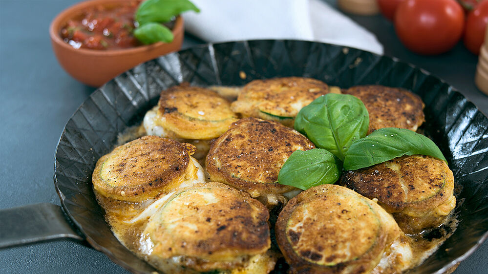 Überbackene Zucchini-Mozzarella-Scheiben in einer gusseisernen Pfanne