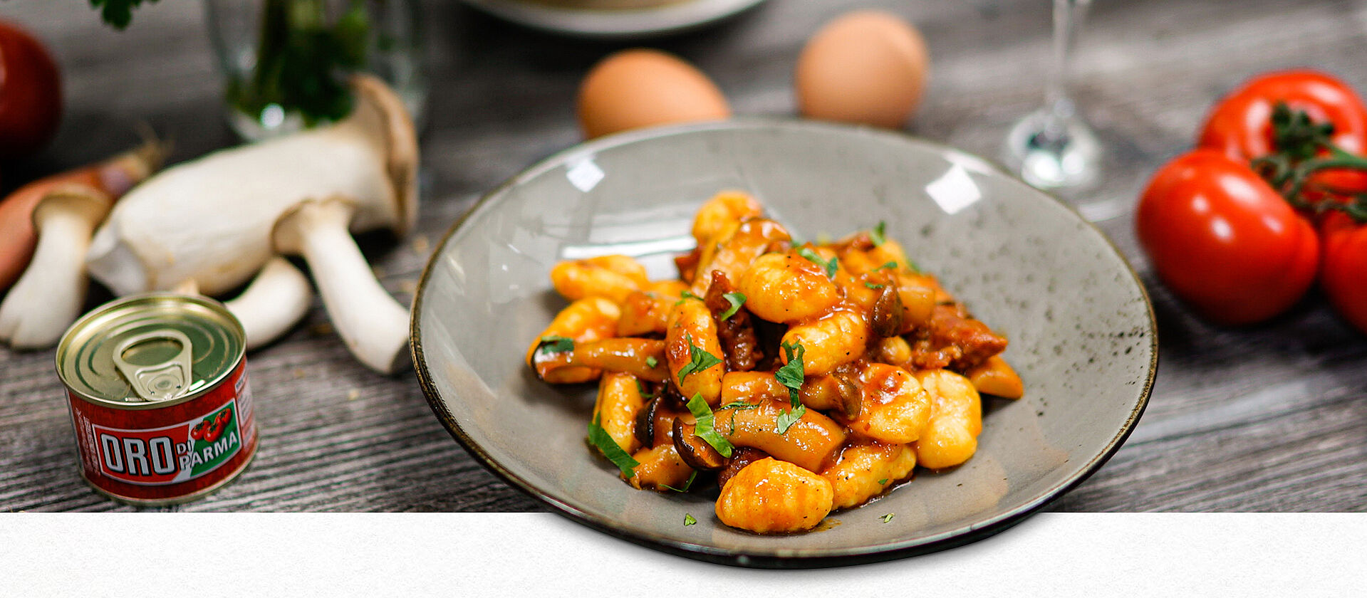 Gnocchi mit Pilzen und Salsiccia auf einem grauen Teller angerichtet