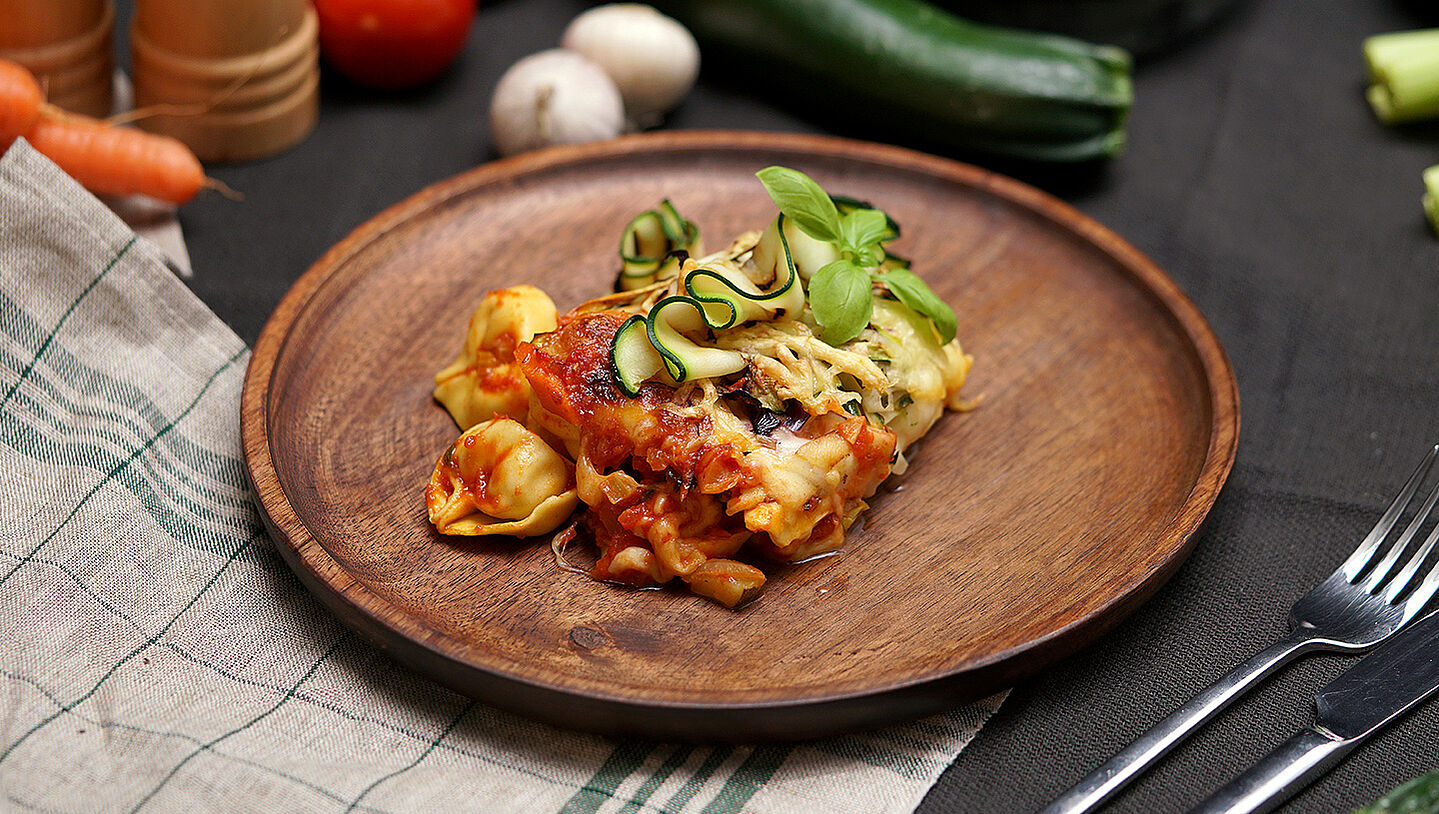 Ein Holzteller mit einer Portion Tortellini al forno