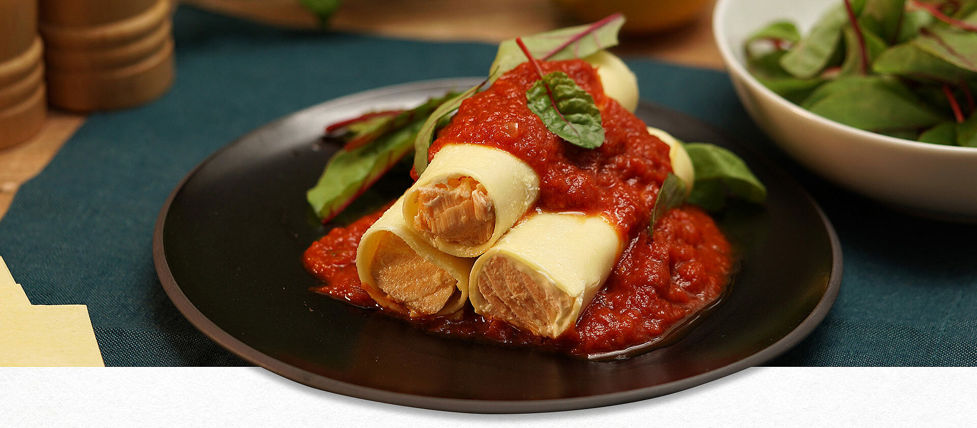 Lachs-Cannelloni mit Tomatensauce auf einem Teller angerichtet