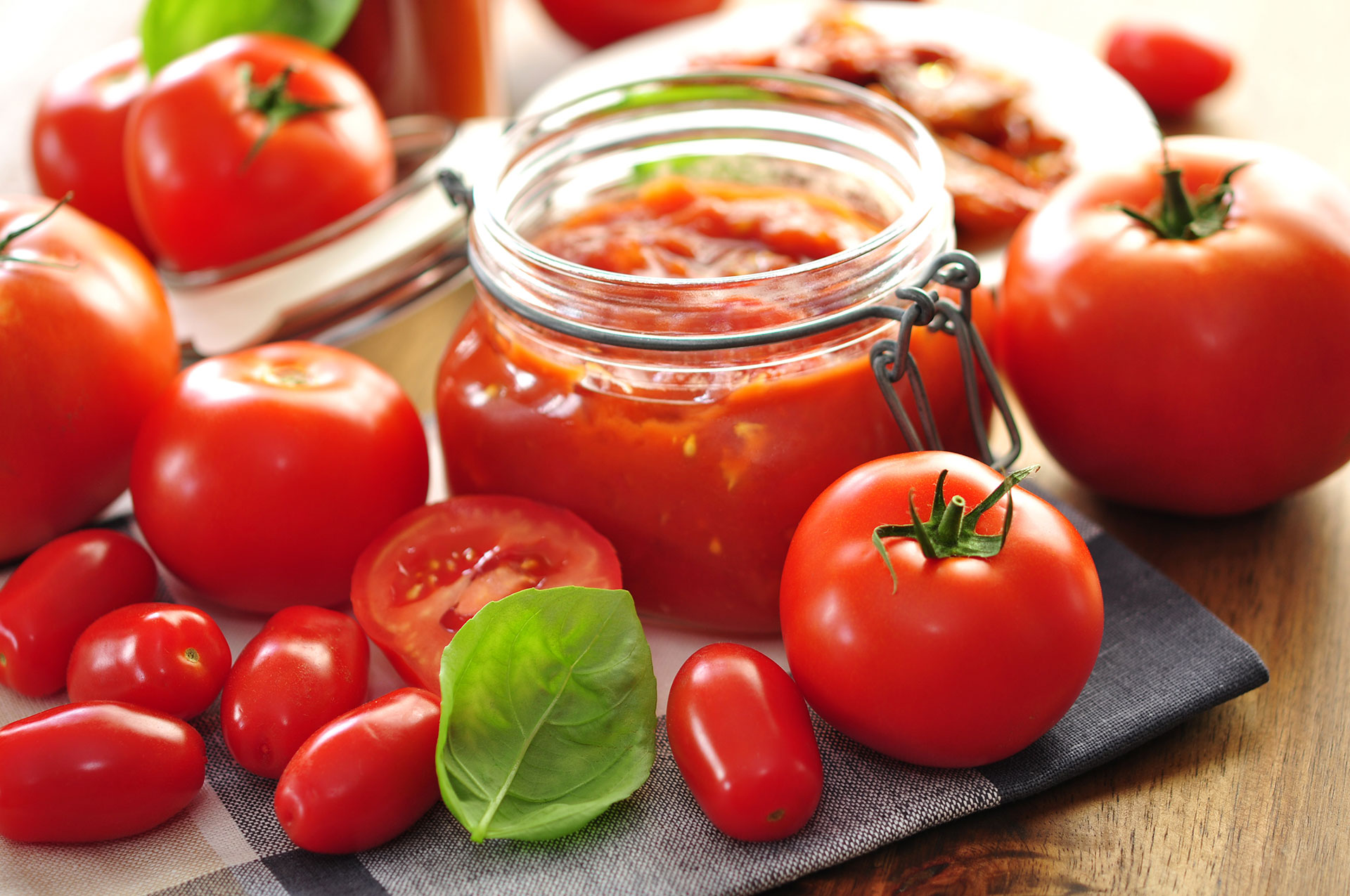 Tomatendip in einem Glas. Rundherum liegen frische Tomaten.