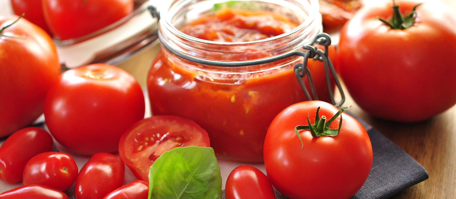 In einem Glas ist ein Tomatendip abgefüllt, drumherum liegen Tomaten