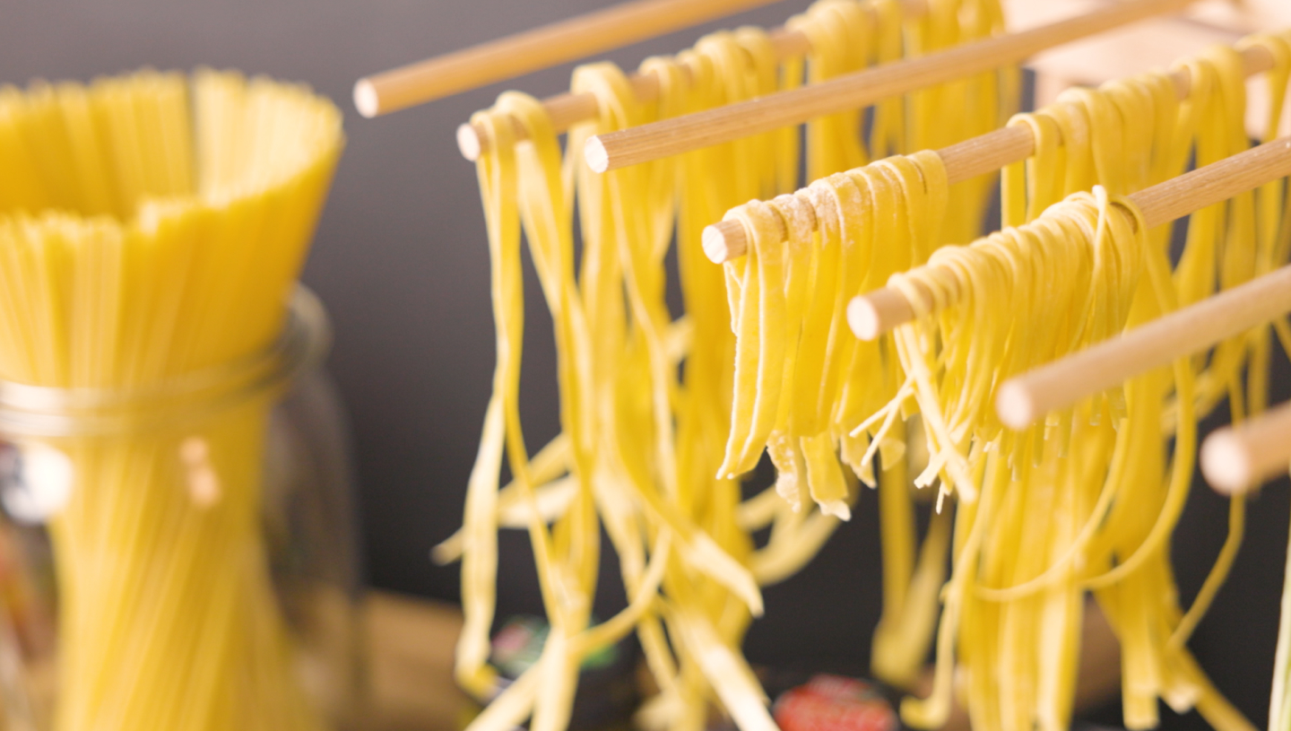 Selbstgemachte Pasta hängt zum Trocknen an Holzstäben