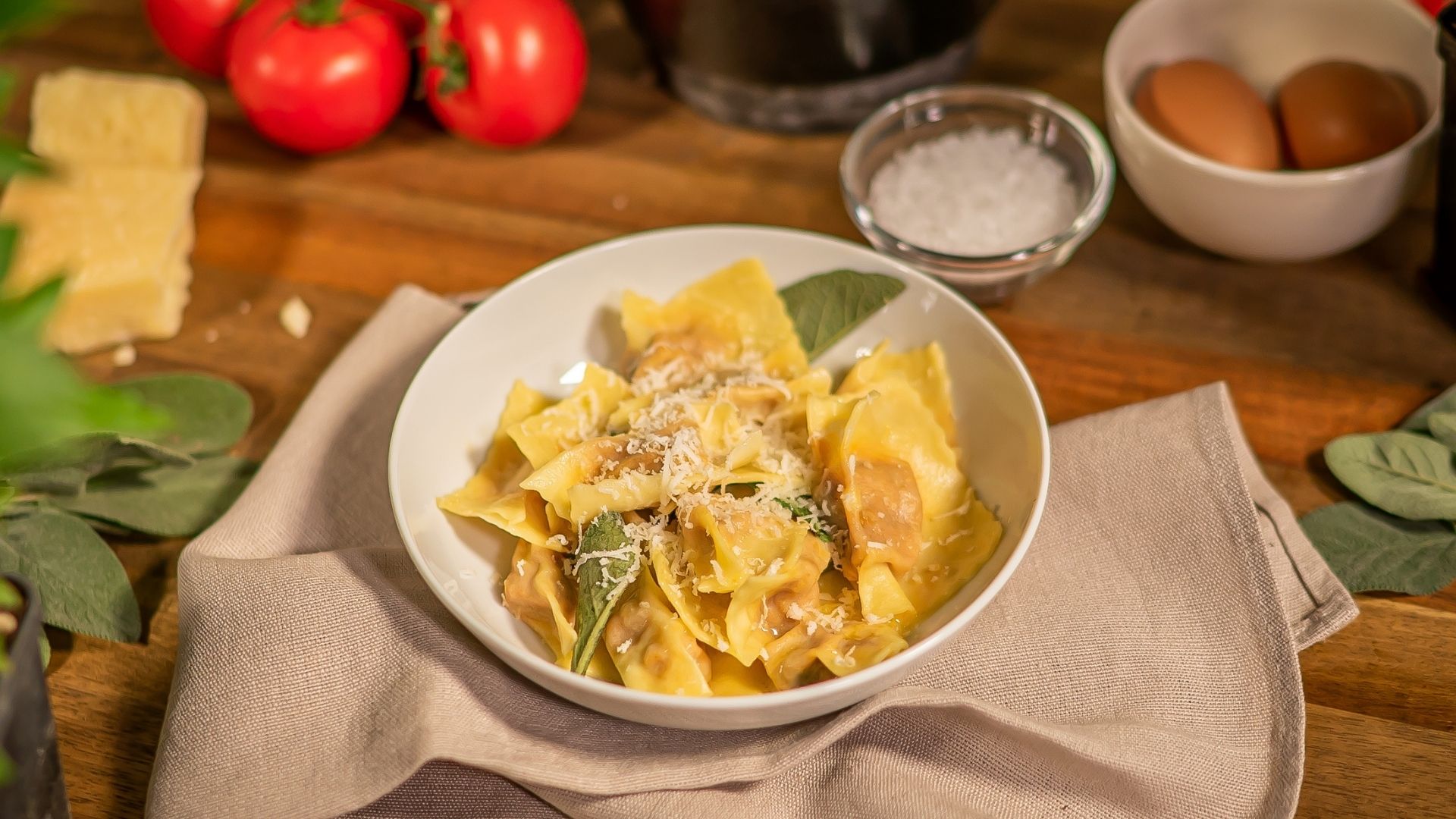 In einer weißen Schüssel sind italienische Agnolotti zu sehen. Die Schüssel steht auf einem beigen Küchentuch. 